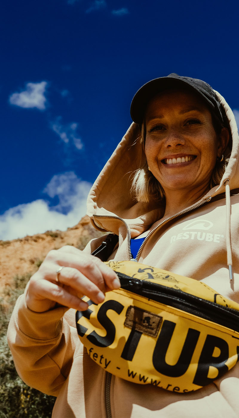 Woman smiling at the camera with a RESTUBE waist pouch – a motivational outdoor moment showing how easy water safety can be.