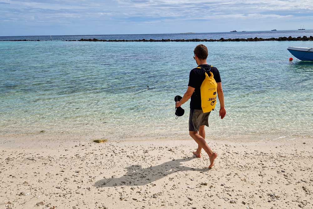 Person with yellow RESTUBE swim buoy sprapped to his back like a rucksack – ready for watersport activities.