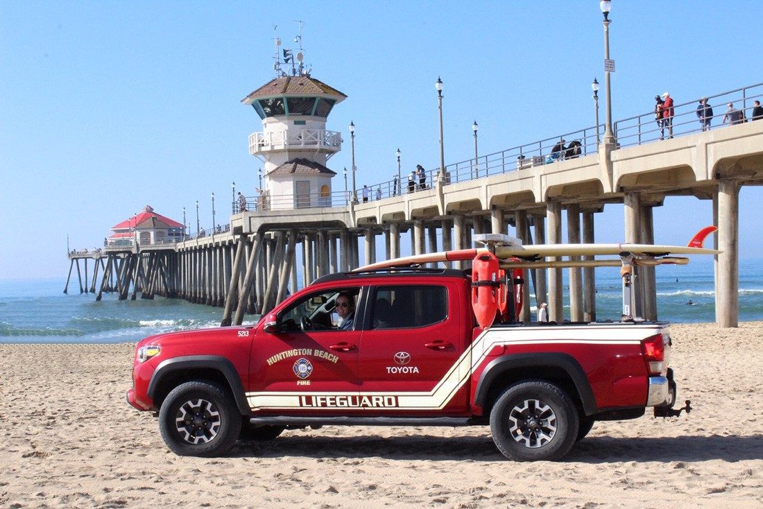 Lifeguard Pick up mit Baywatch-Bojen und Surfbrett auf dem Dach.