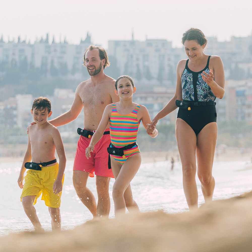 Familie mit 2 Kinder und eine extra Portion Sicherheit durch die getragenen Restube am Strand.
