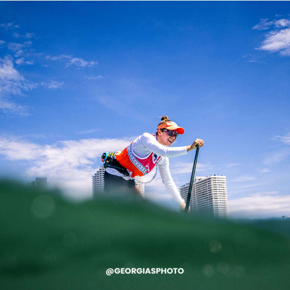 A Paddler with RESTUBE buoy on the water with a cityscape in the background on a sunny day.