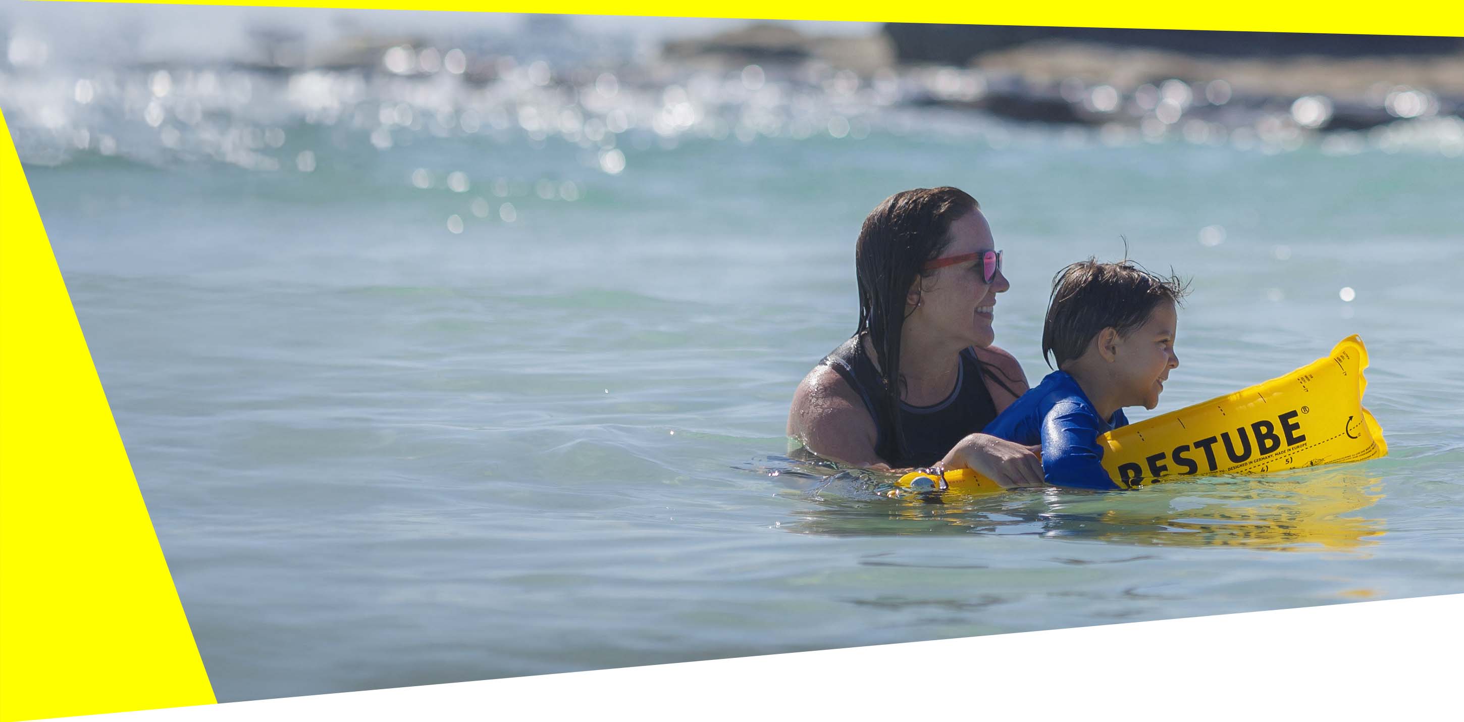 An adult and a child with RESTUBE buoy in the water – for safety and flotation.
