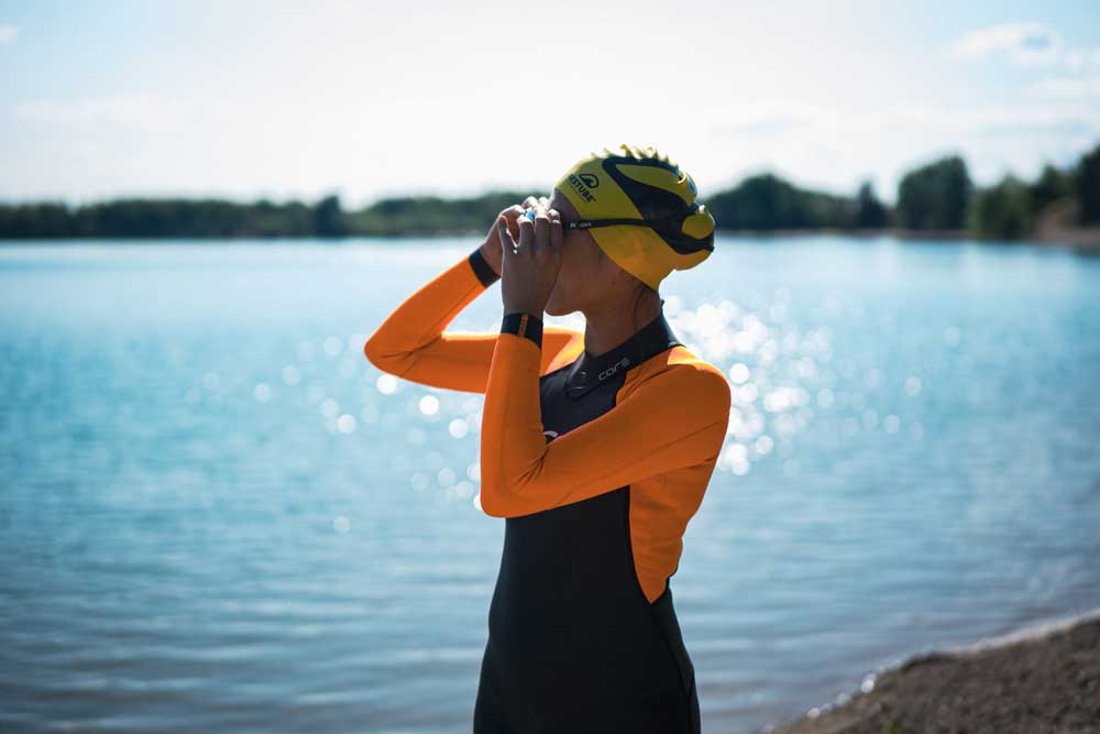 Swimmer in wetsuit and swim cap at the lake shore – ready for watersports.
