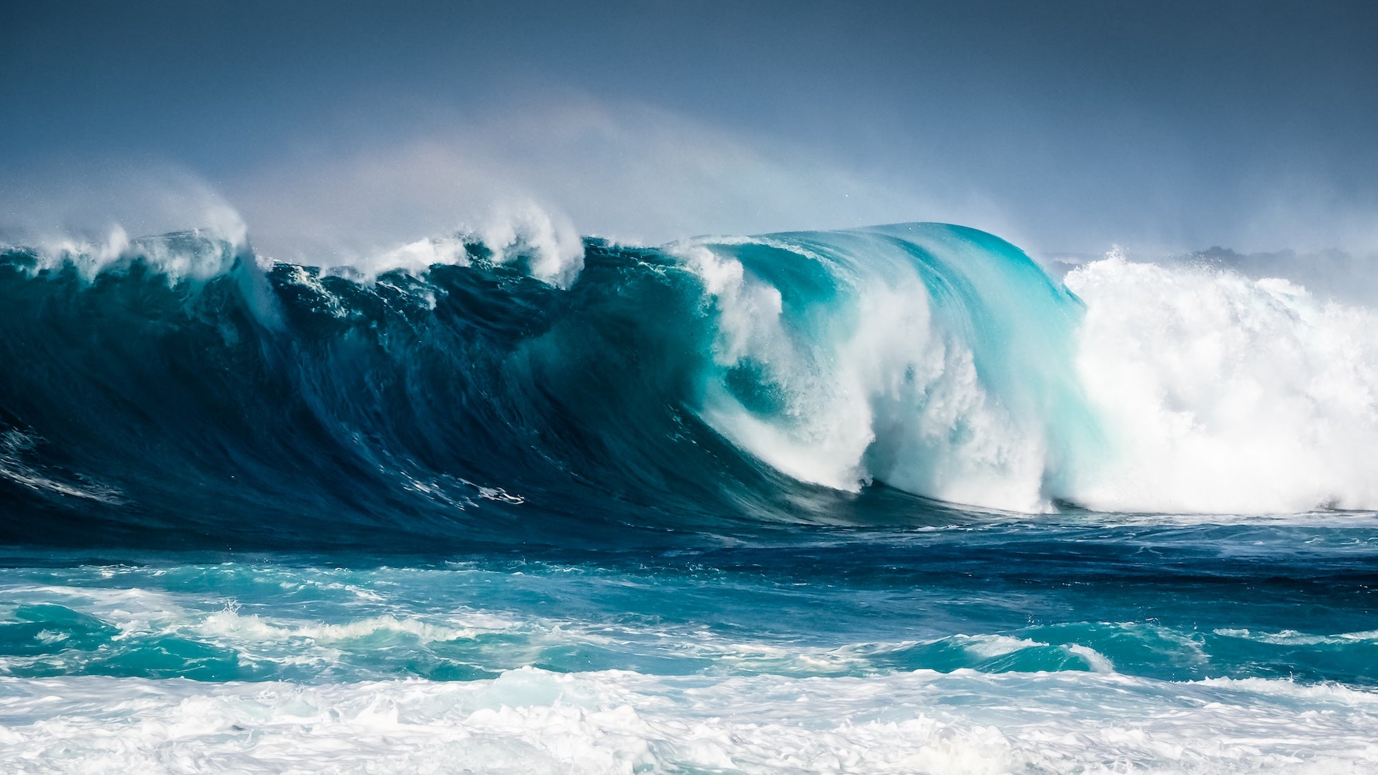 Powerful breaking surf wave with white foam and spray, showing the enormous energy of ocean waves in the surf zone