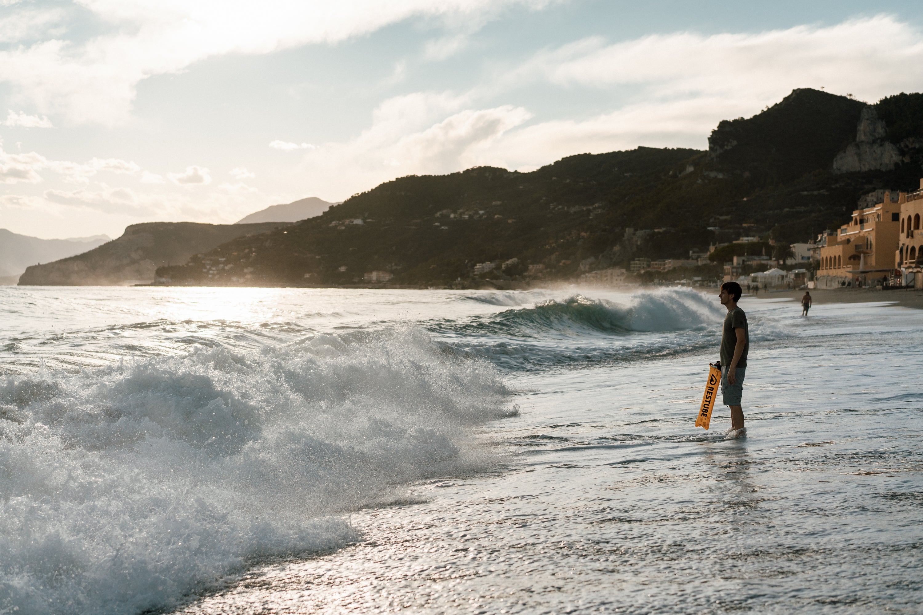 Watersports athlete with RESTUBE buoy on the beach at sunset.