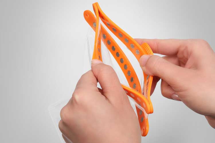 Person holding a waterproof pouch with orange closing parts – shows flexibility and user-friendliness.