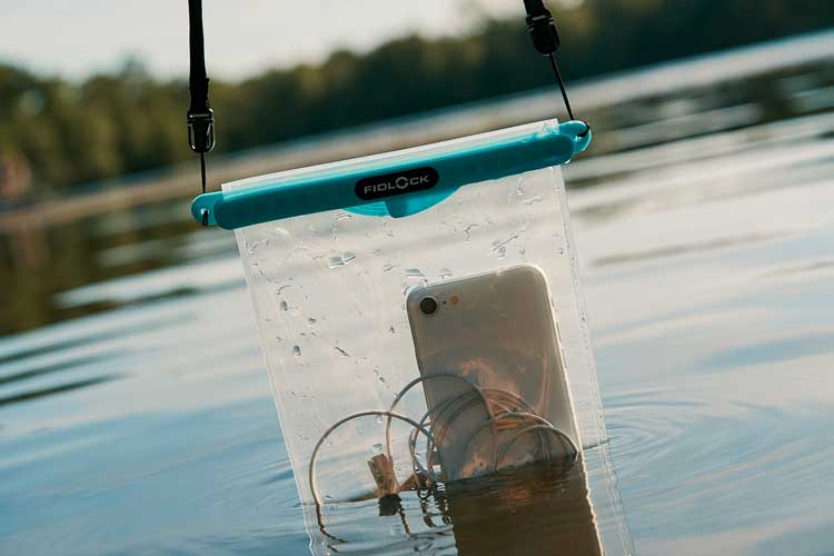 Waterproof pouch submerged to half into a lake with visible smartphone and a bunch of cords.