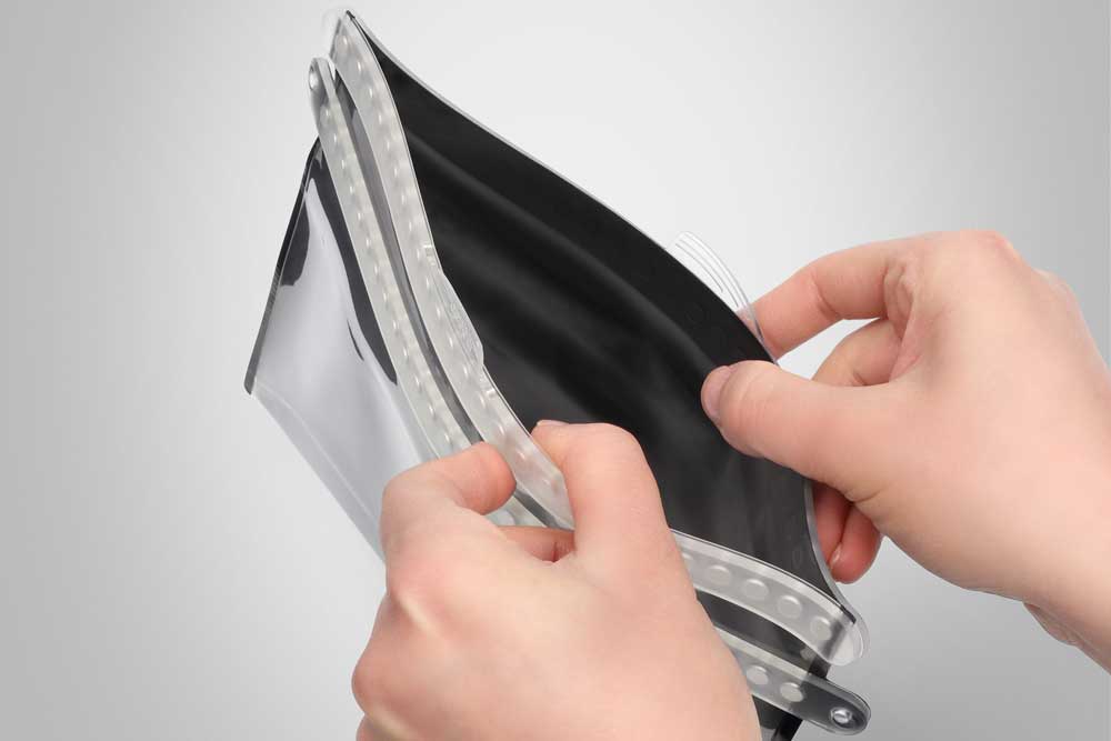 Waterproof pouch being opened by hand.