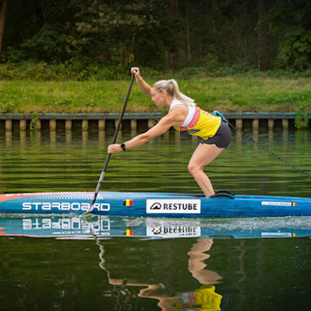 Paddler with RESTUBE buoy on a SUP board on a calm river, competing in a tournament.