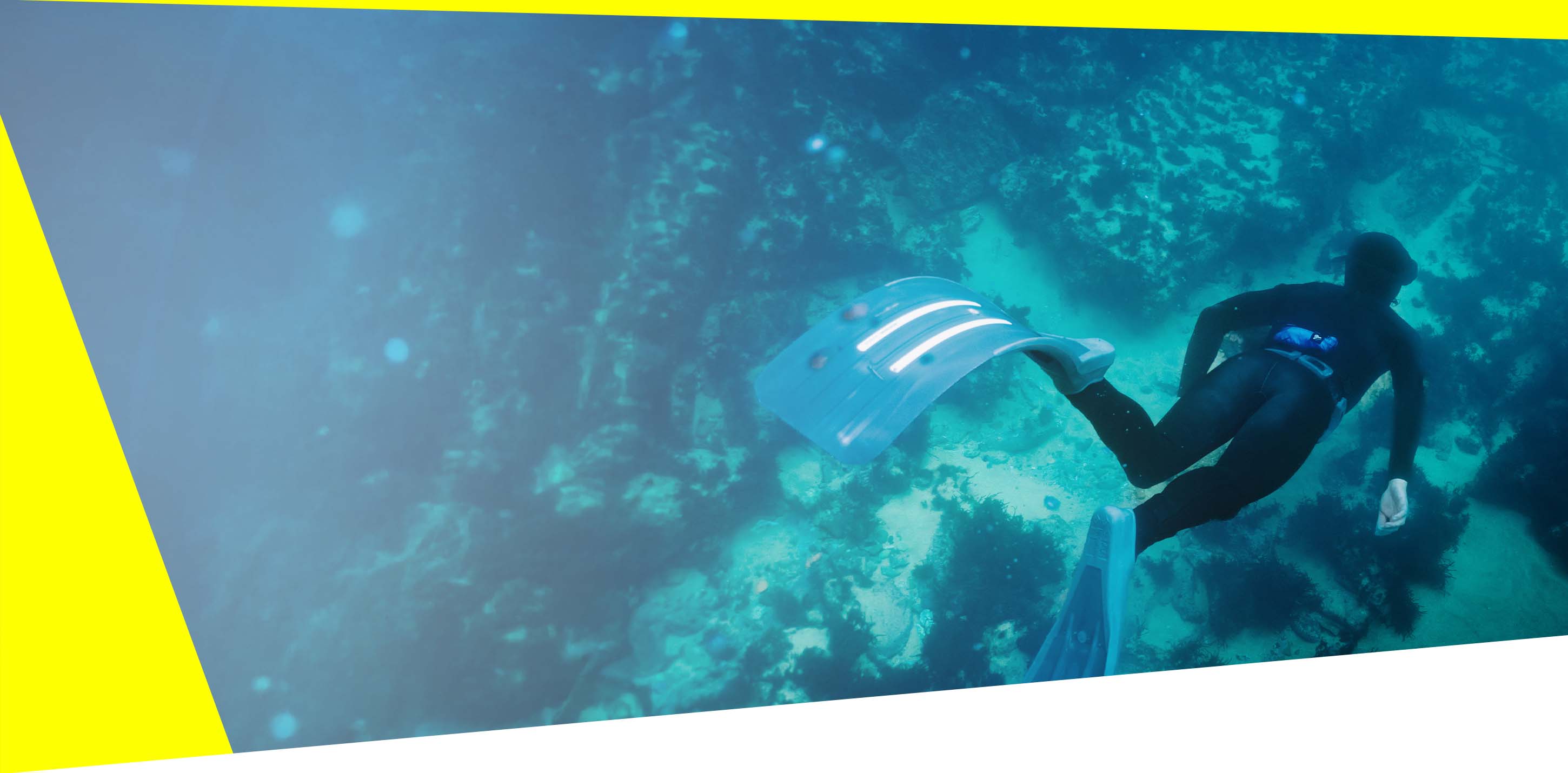 Diver with RESTUBE buoy in clear water inspecting the ocean ground – for freediving safety.