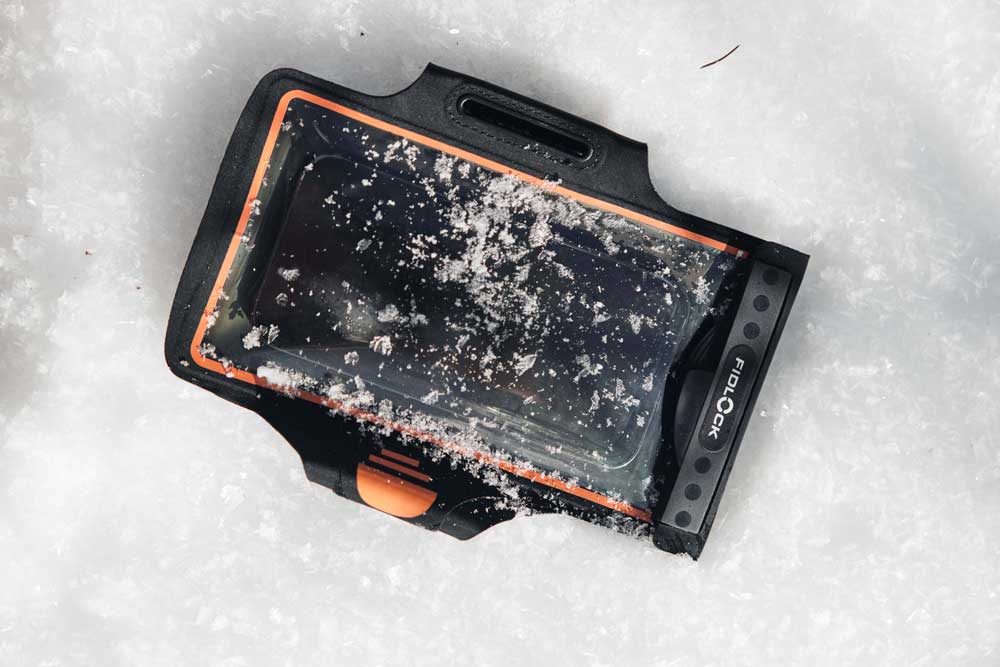 Waterproof phone case lying in the snow with a phone inside.