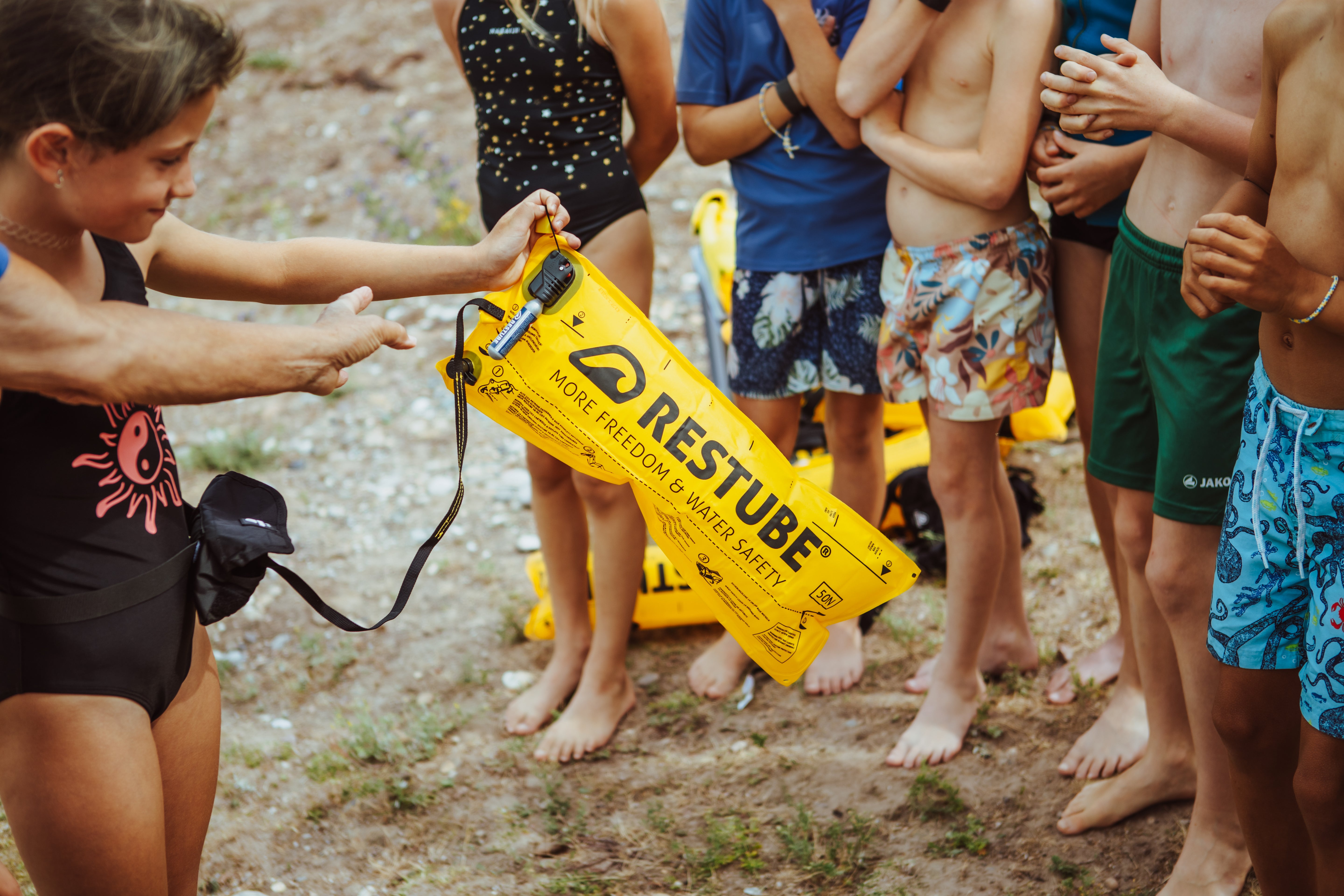 Child showing yellow RESTUBE safety buoy during water safety demo.
