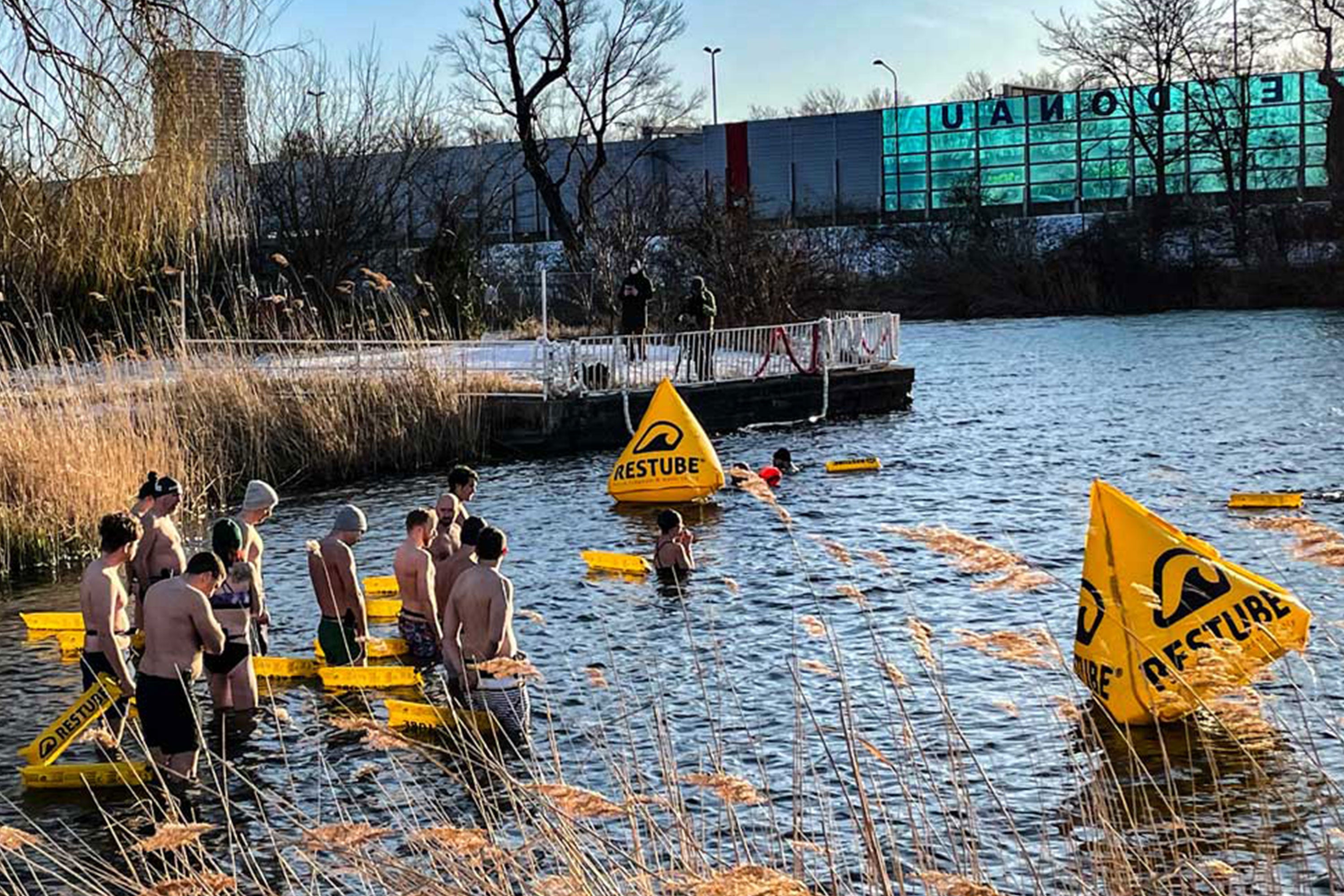 Multiple participants in a water safety drill with RESTUBE safety buoys and race buyos in a lake.