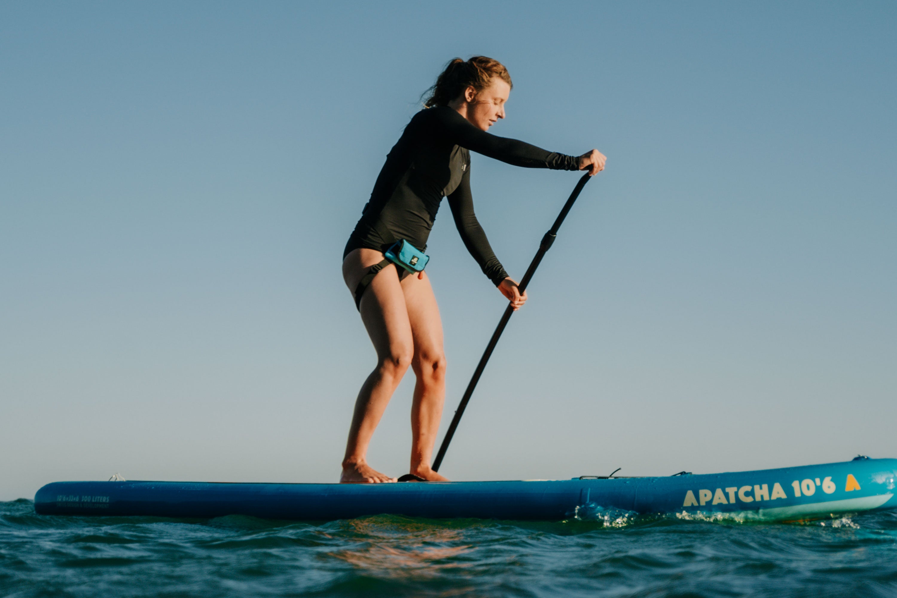 Woman stand-up paddling with RESTUBE buoy – for safety on the sea.