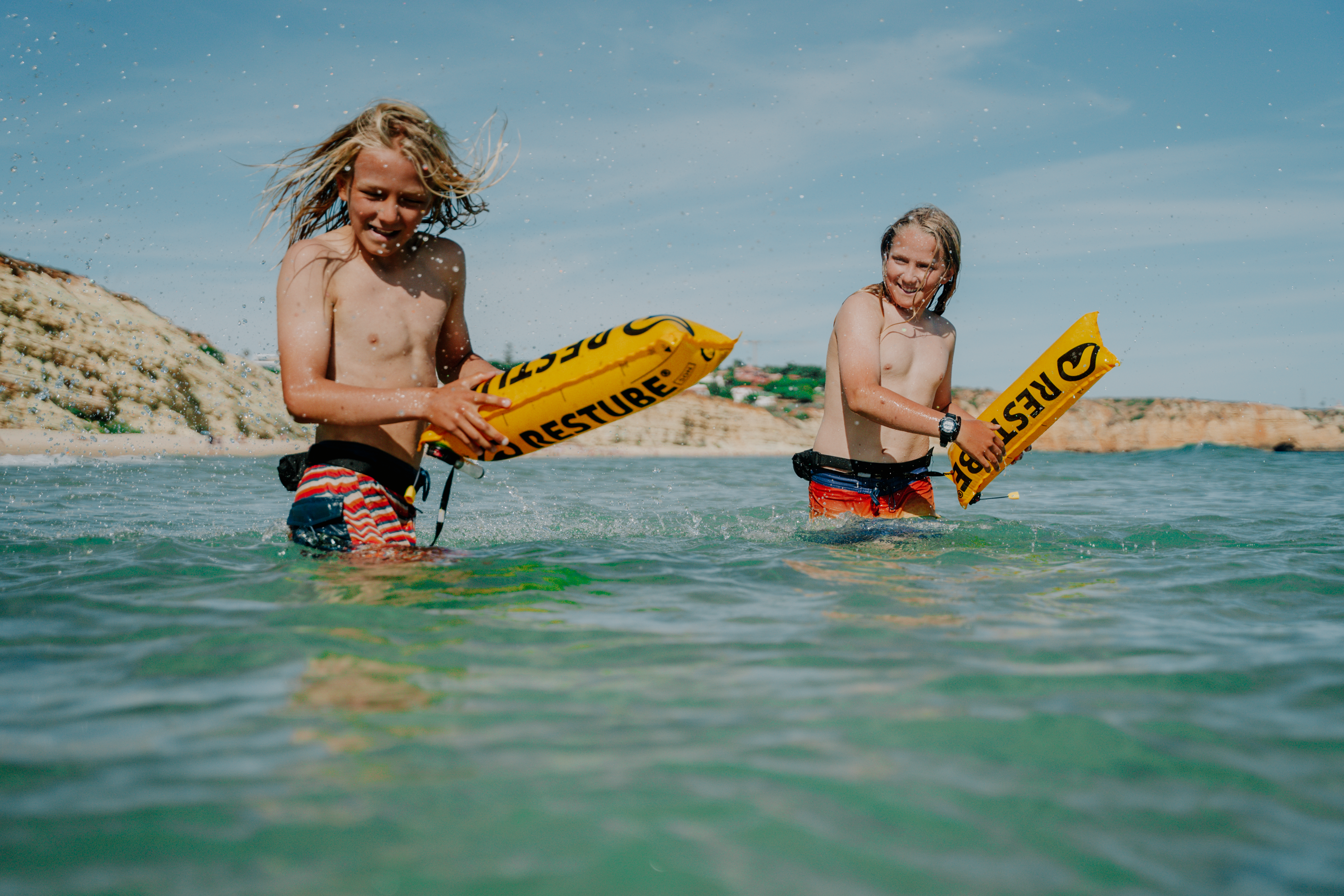 Two children with RESTUBE safety buoys in the water – for swimming safety.