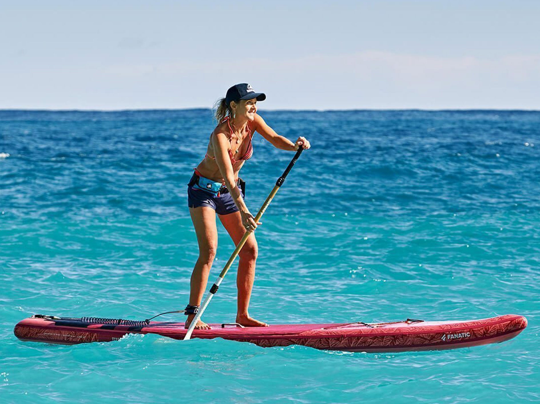 Woman stand-up paddling with RESTUBE buoy – for safety on the sea.