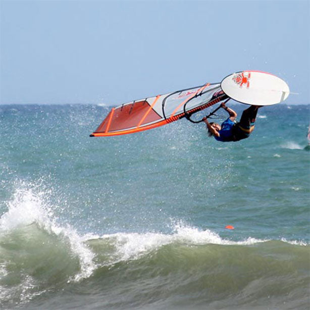 Windsurfer with RESTUBE buoy jumping over a wave in the sea.