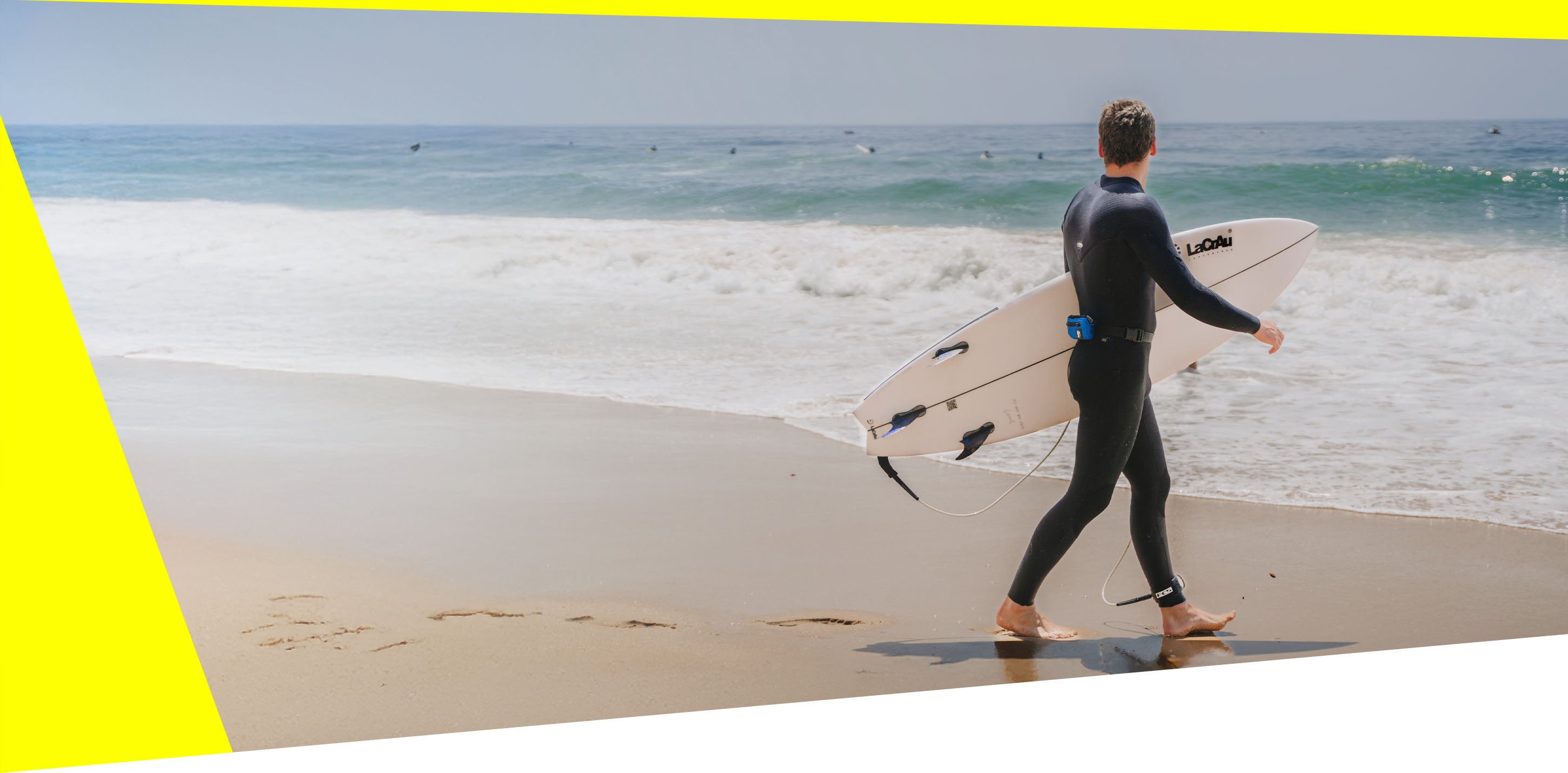 Surfer with RESTUBE buoy standing on the beach watching the waves.