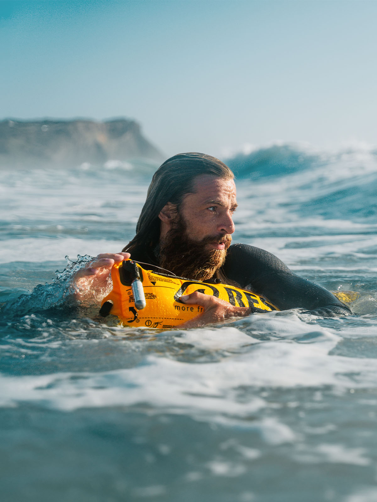A Man in the water with an inflatable RESTUBE safety buoy for watersports.