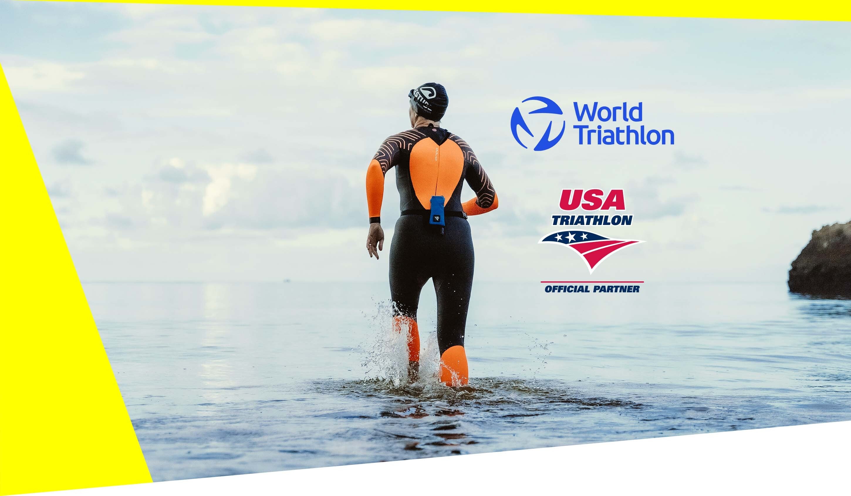 Triathlete entering open water wearing a wetsuit with safety buoy, World Triathlon and USA Triathlon official partner branding