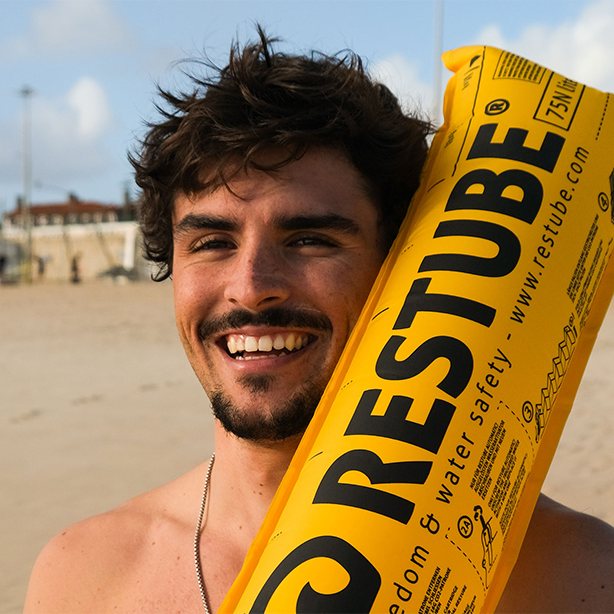 Happy man smiling with RESTUBE safety buoy on the beach.