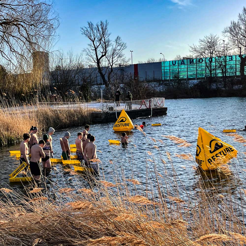 Multiple participants in a water safety drill with RESTUBE safety buoys and race buyos in a lake.