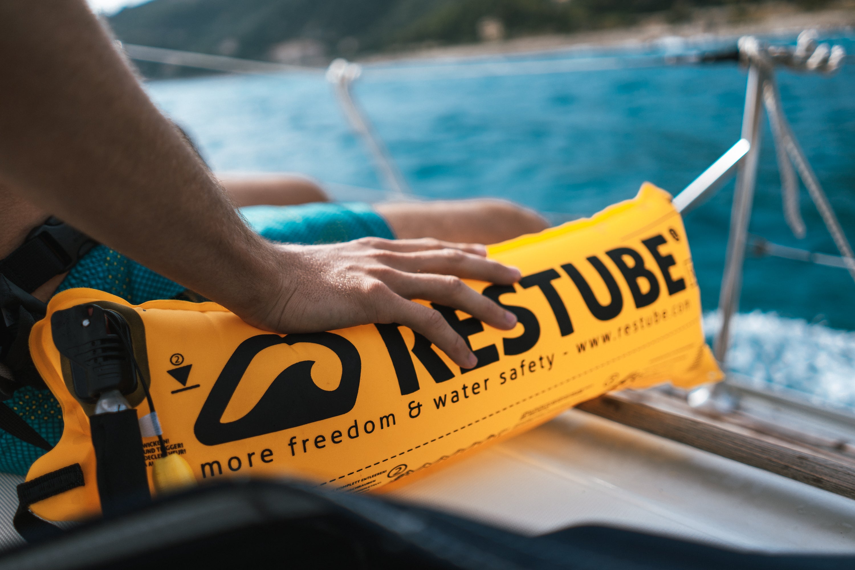 A person holding yellow RESTUBE safety buoy on a boat – ready for water deployment.
