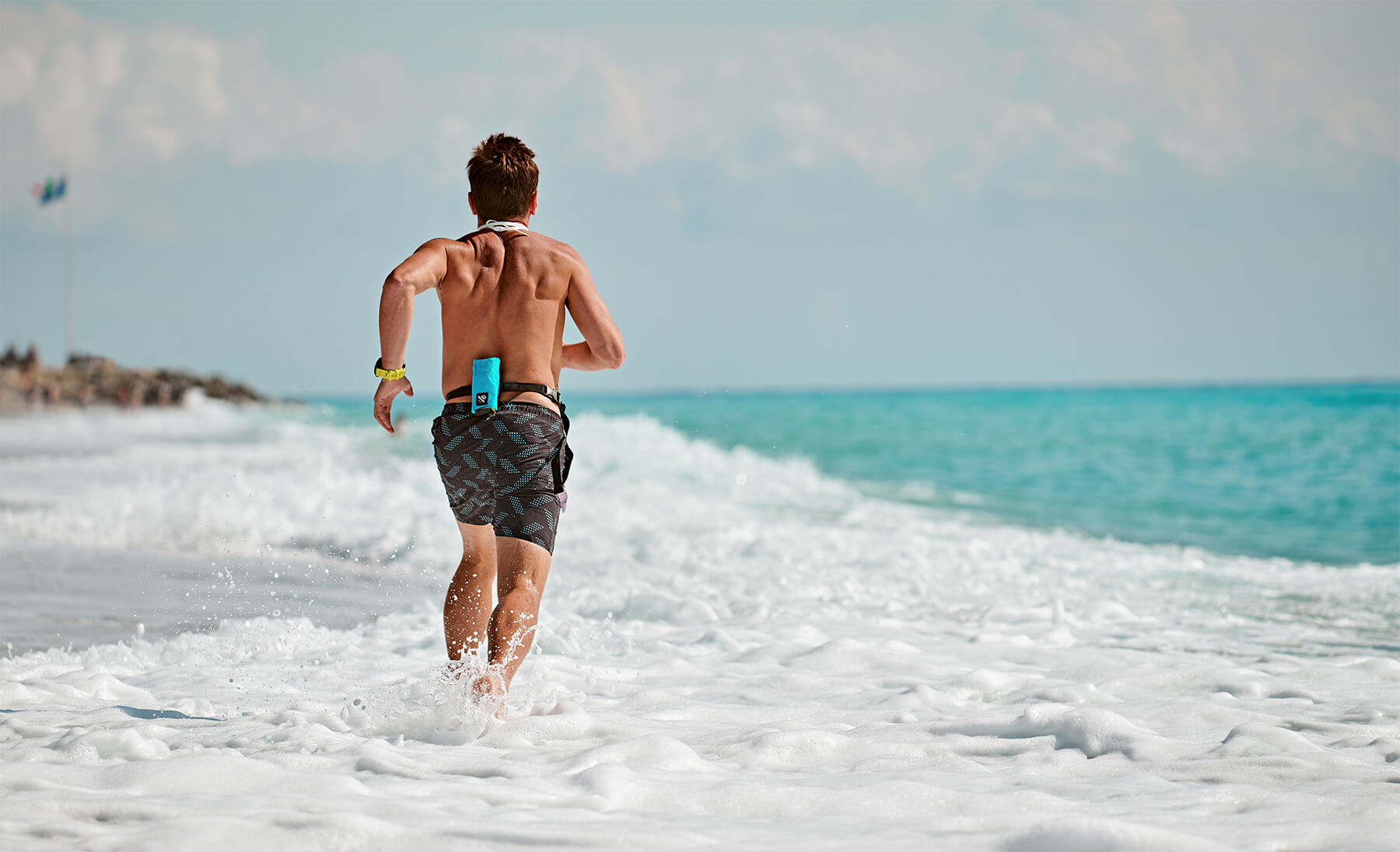 Loic Branda joggt mit Restube active am Strand durch das Wasser