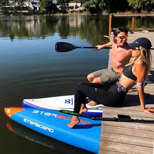 Couple on dock with paddles and SUP boards – ready for watersports.
