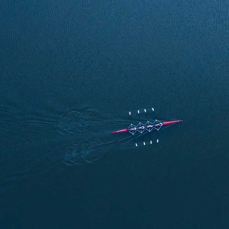 Rowing boat with four athletes on calm water – symbolizes water safety and teamwork in sport.