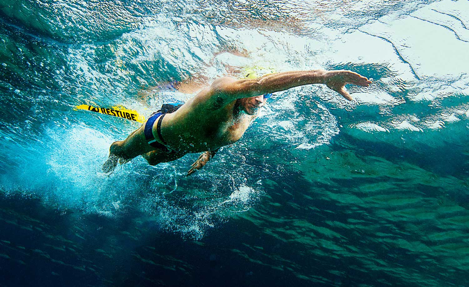 Long distance swimmer in the water, pulling a restube buoy behind himself