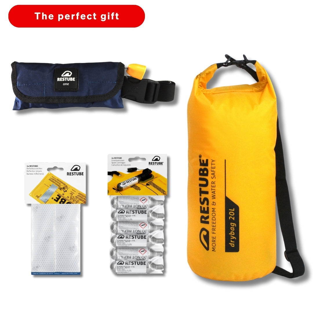 RESTUBE gift set featuring a yellow 20L dry bag, a RESTUBE ONE safety buoy, CO₂ cartridges, and reflector strips; red label saying “The perfect gift.”