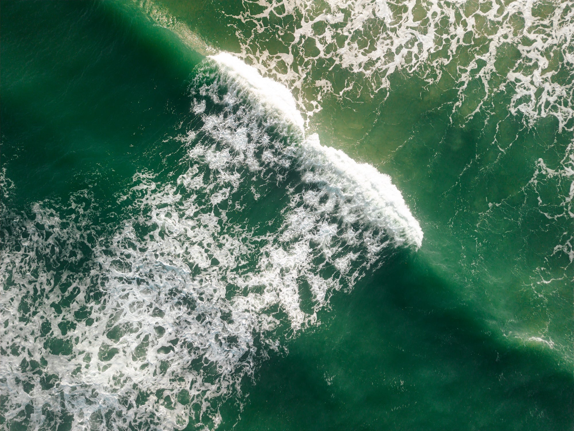 Aerial view of ocean foam and sea spray showing wave break patterns and surface currents: visible indicators of rip currents and water movement