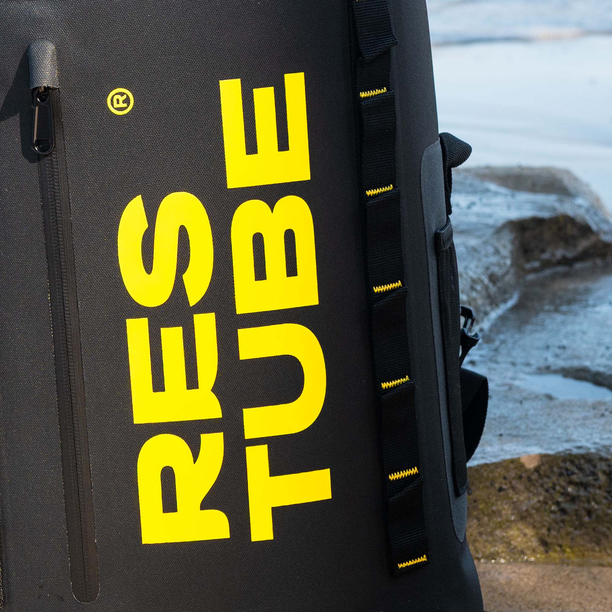 Close-up of RESTUBE waterproof backpack with bold yellow logo, highlighting durable material, zipper detail, and attachment loops