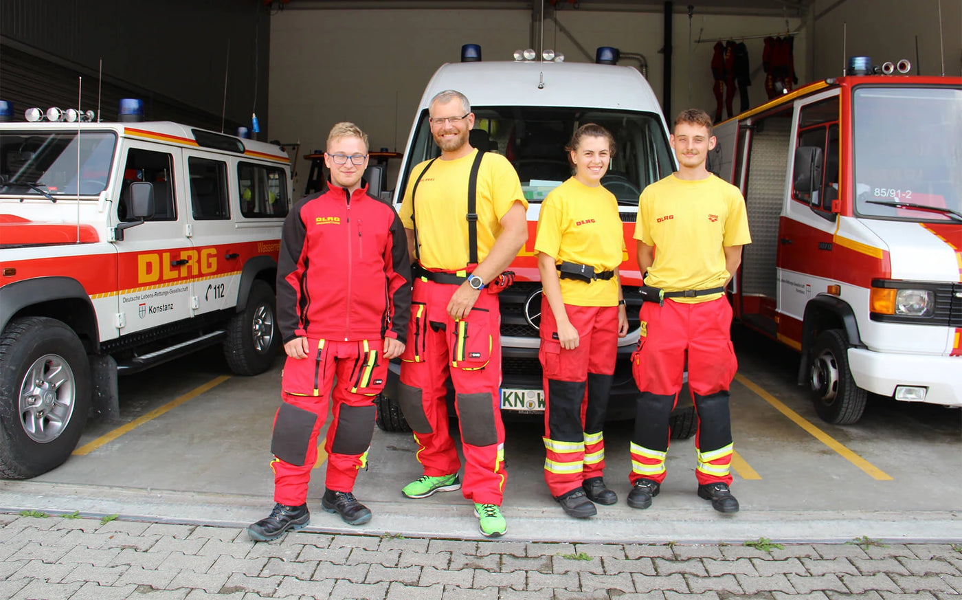 DLRG Lifeguards Konstanz, Rettungsschwimmer mit Restube-Bojen-Gürtel vor Ihren Fahrzeugen.
