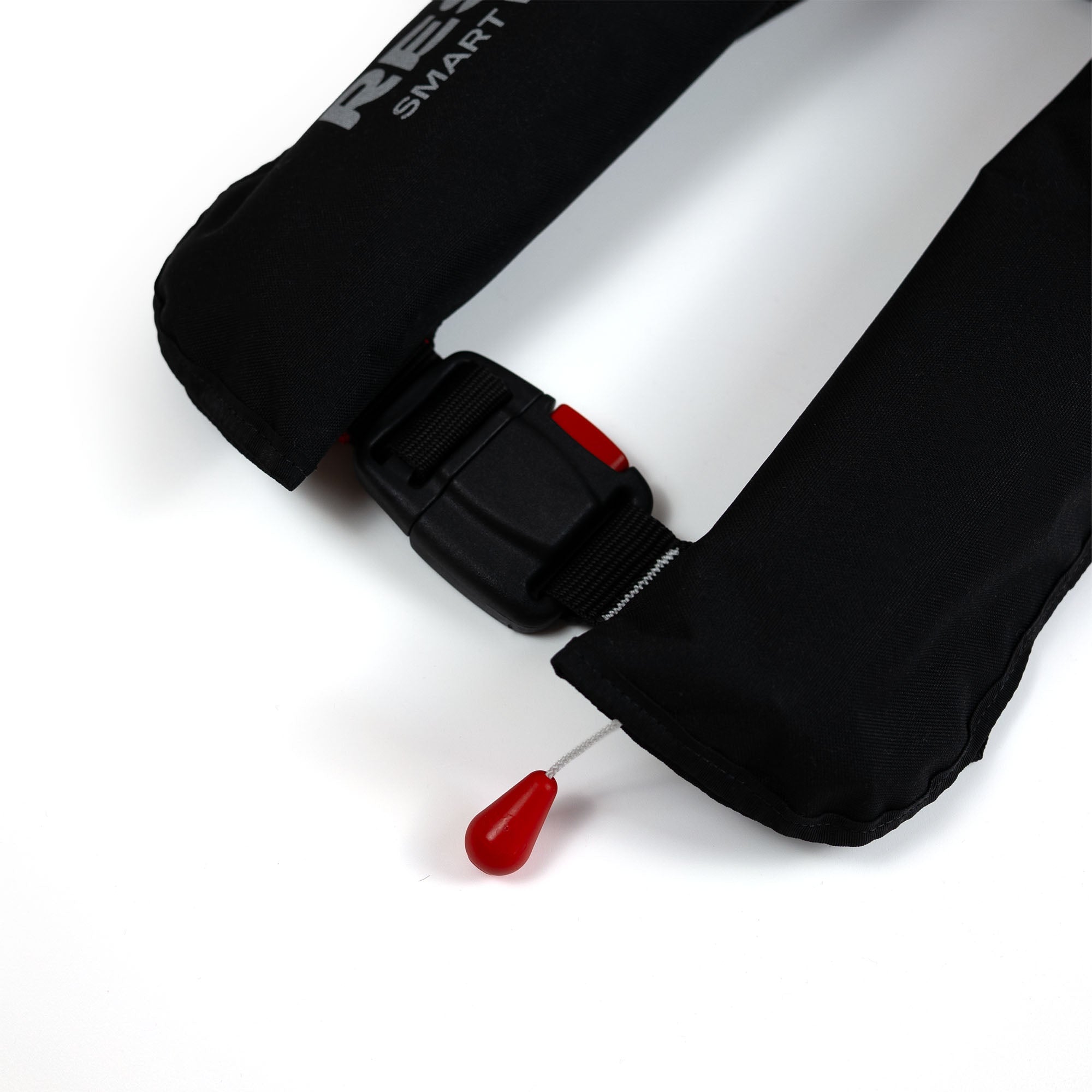 Close-up of plastic buckle and red pull cord trigger on inflatable life jacket