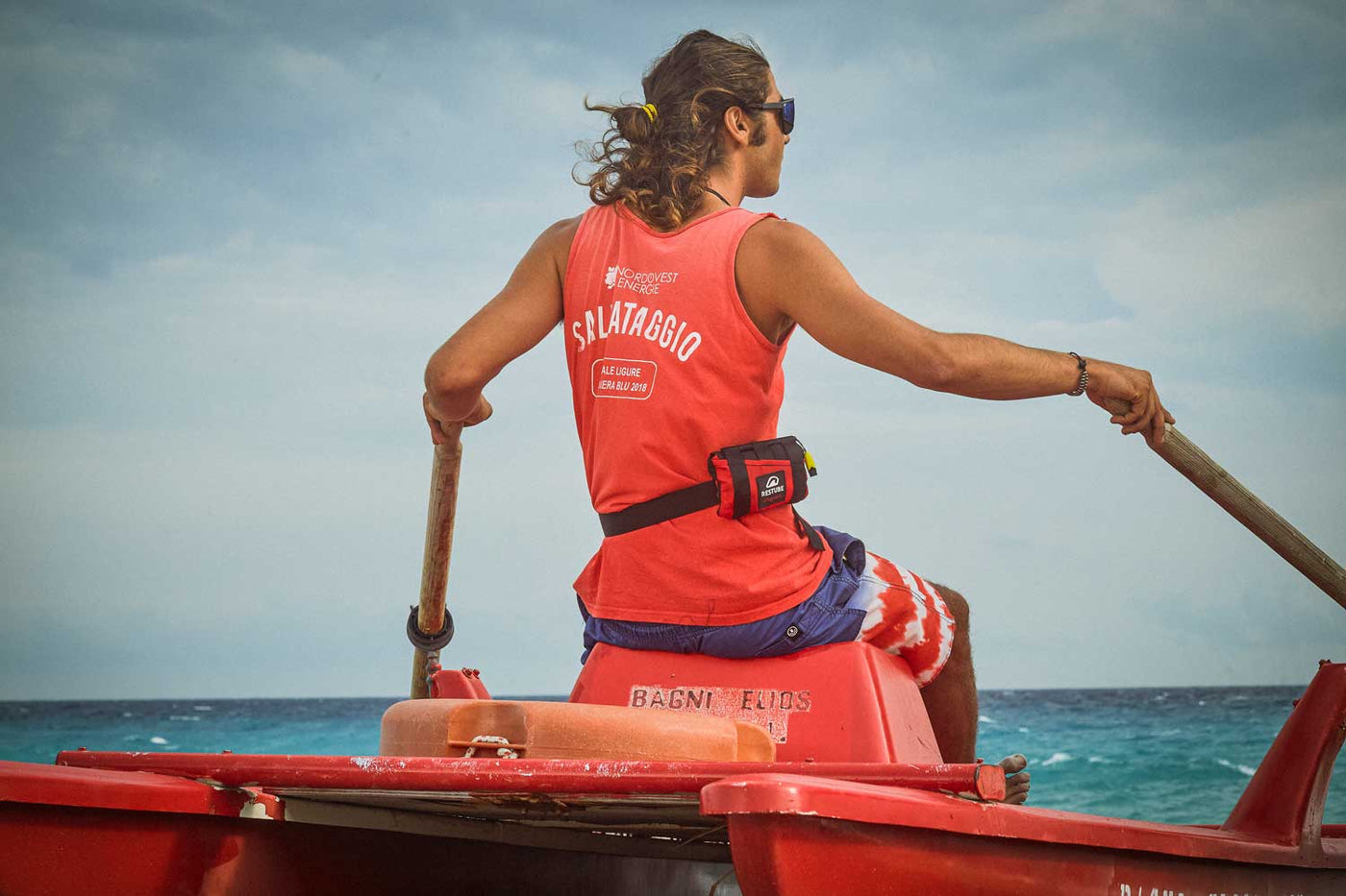 Rettungsschwimmer mit Restube Lifeguard sitzt auf Katamaran und beobachtet das Meer.
