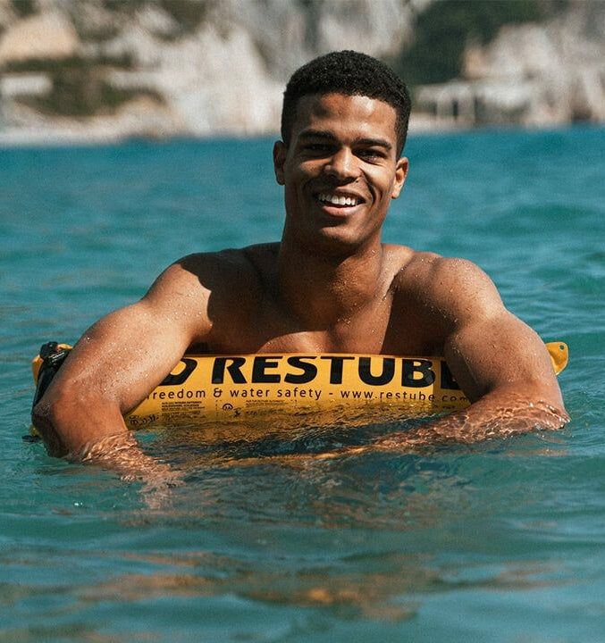 Mann relaxt im Meer auf seiner Restube Schwimmboje.