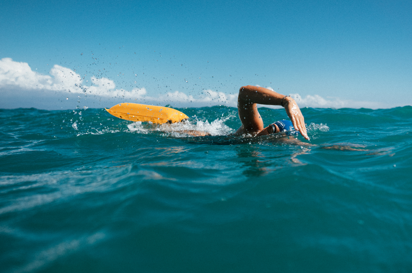 Schwimmerin beim Langstreckenschwimmen im freien Wasser zieht Restube Boje hinter sich her