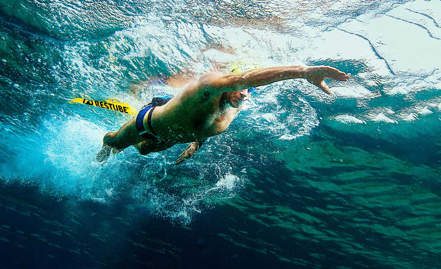 Langstreckenschwimmer von unter Wasser fotografiert zieht Restube Boje hinter sich her.