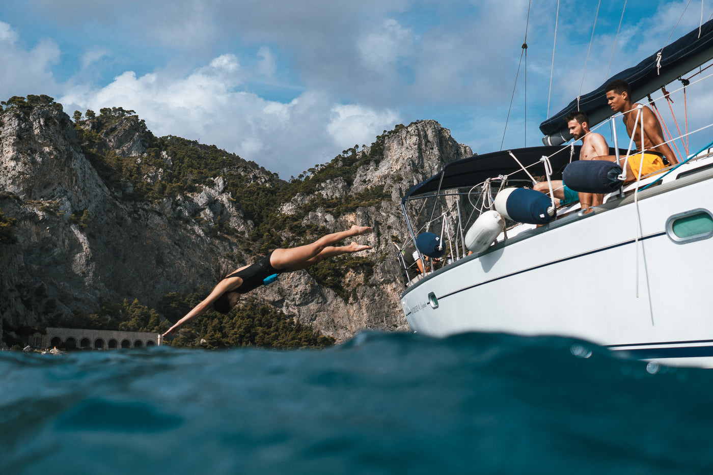 Frau springt mit Kopfsprung und restube Schwimmboje von Segelyacht