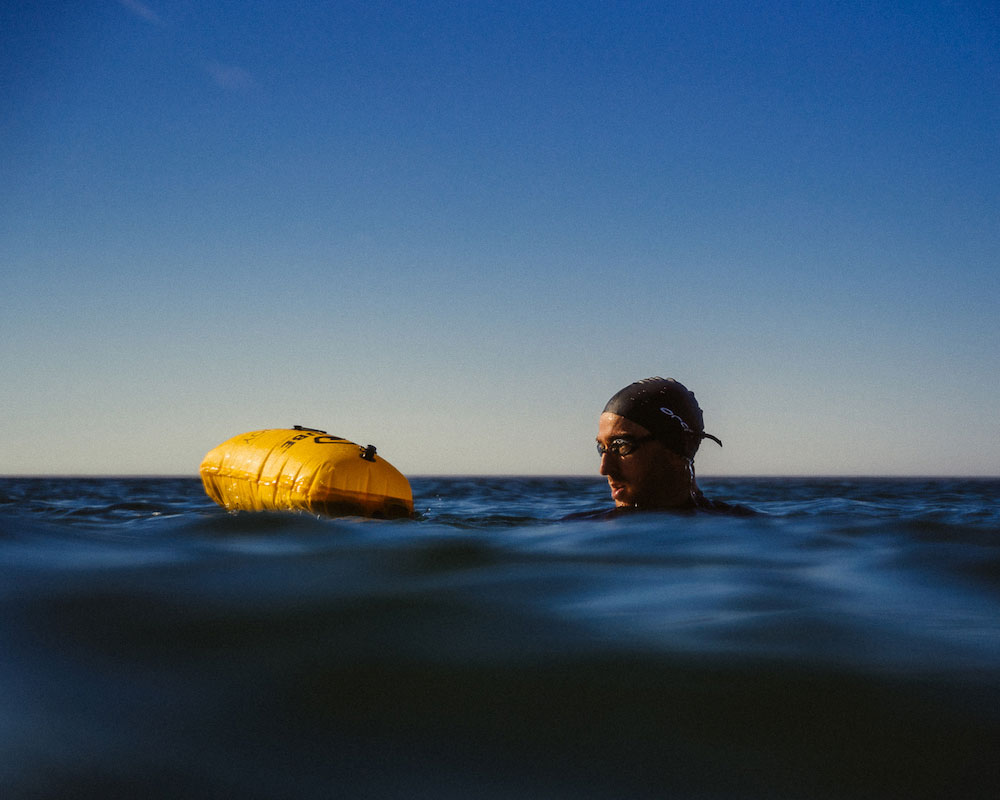 In the water with the swim buoy by RESTUBE looking around with the buoy next to him clearly visbible in the water