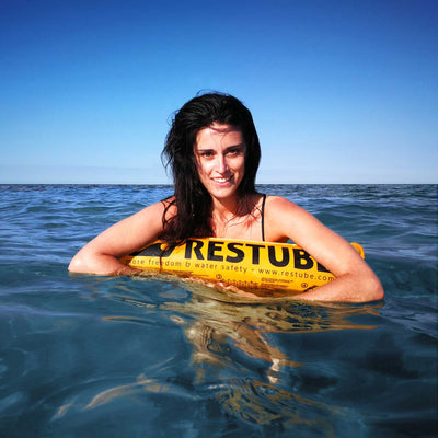 Frau lehnt sich im Meer auf die Restube beach und lächelt in die Kamera