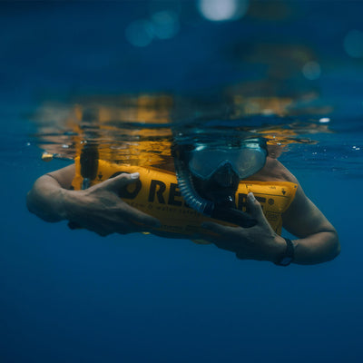 Schwimmer schnorchelt entspannt über Restube Boje gelehnt